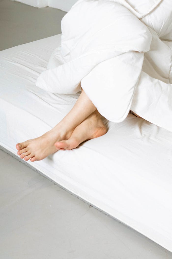 why-choose-us-01 A peaceful scene of bare feet resting on a bed, wrapped in cozy white bedding.