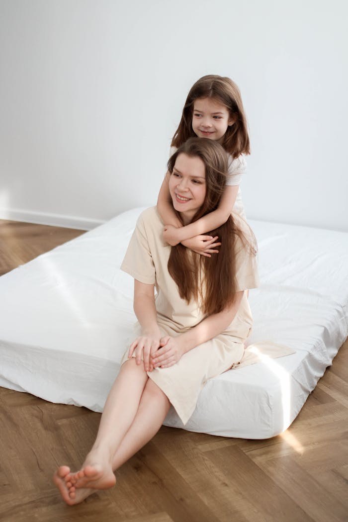 A mother and daughter share a joyful moment together on a bed, showcasing love and bonding.